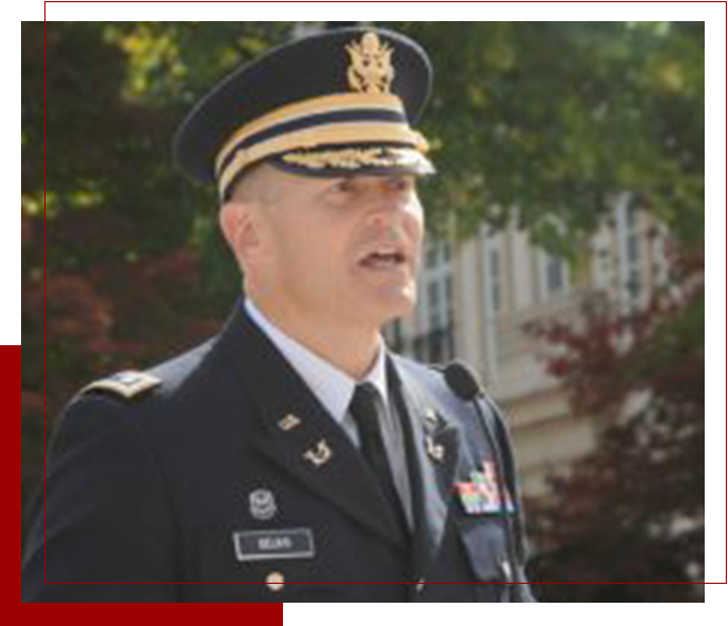 A man in military uniform standing outside.